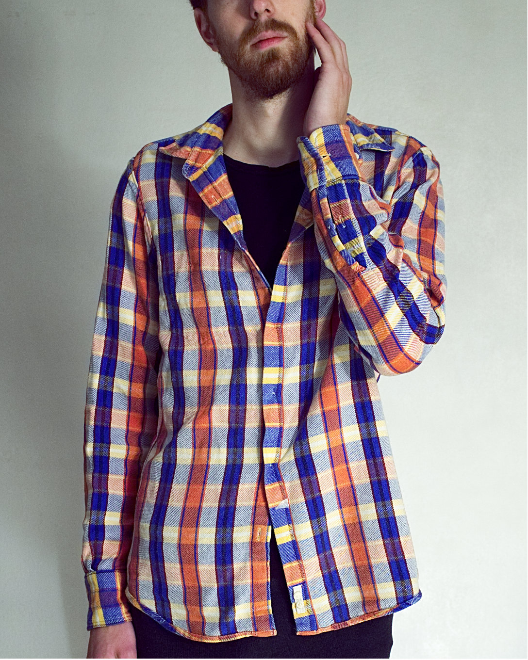Model wears a blue and orange plaid shirt, their eyes are outside the frame hidden